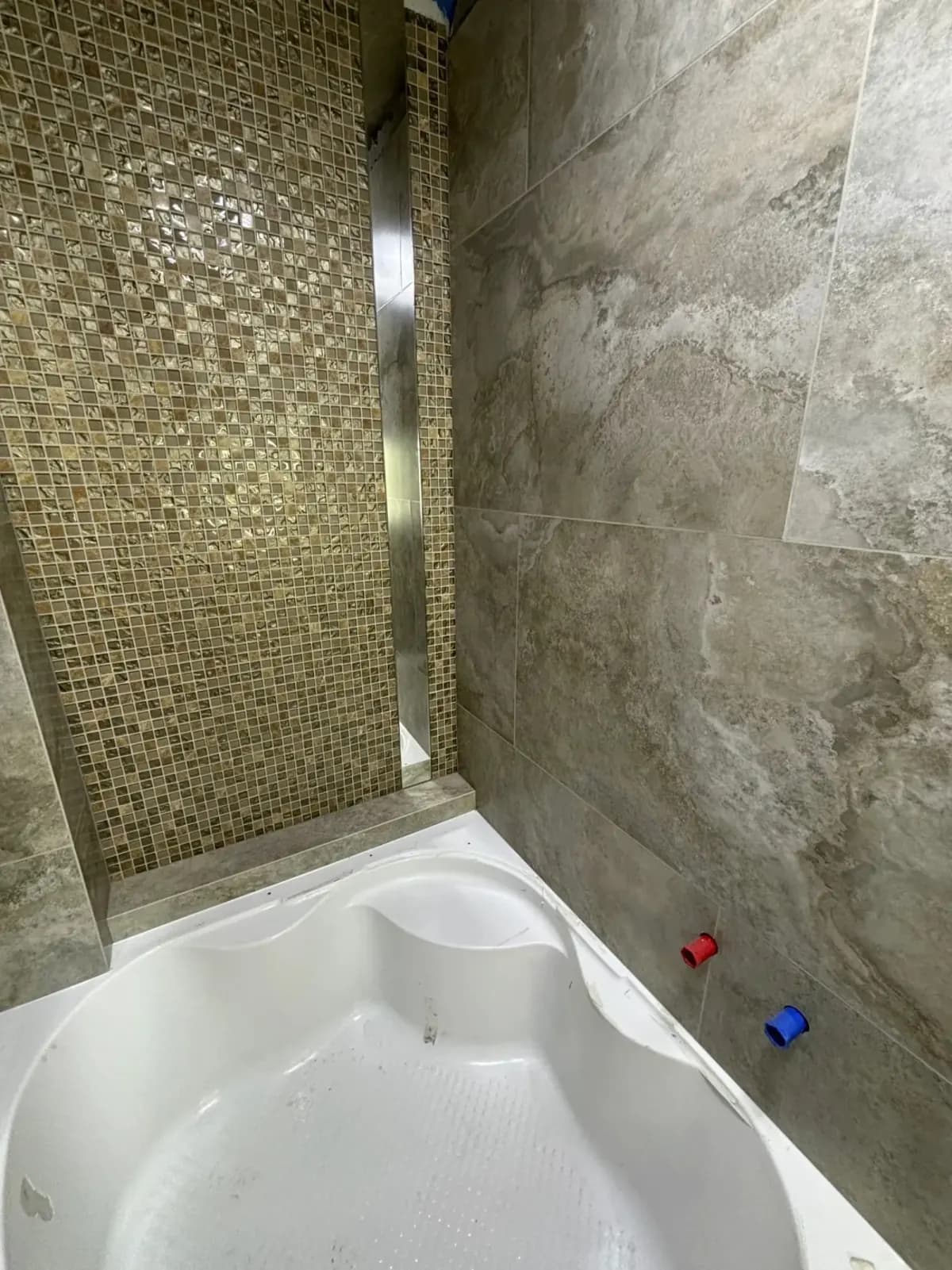 Graues Bad mit Mosaik, Wanne und integrierter Ablage